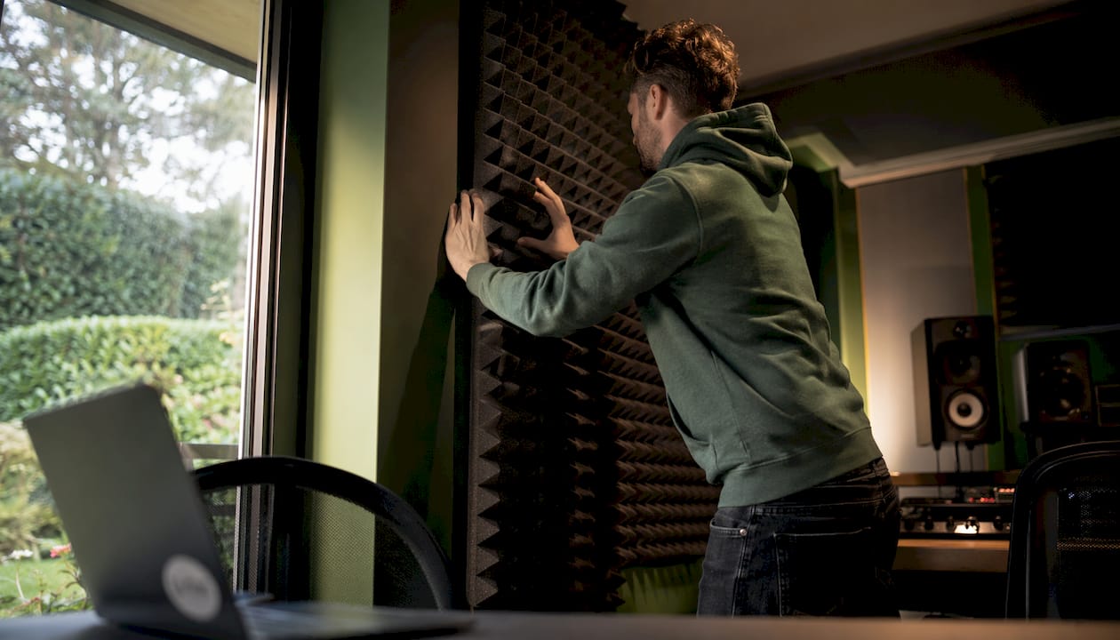 Studioschuim werking uitgelegd voor geluidsprofessionals 4 Een technicus stelt een geluidsisolatiepaneel van studioschuim af.