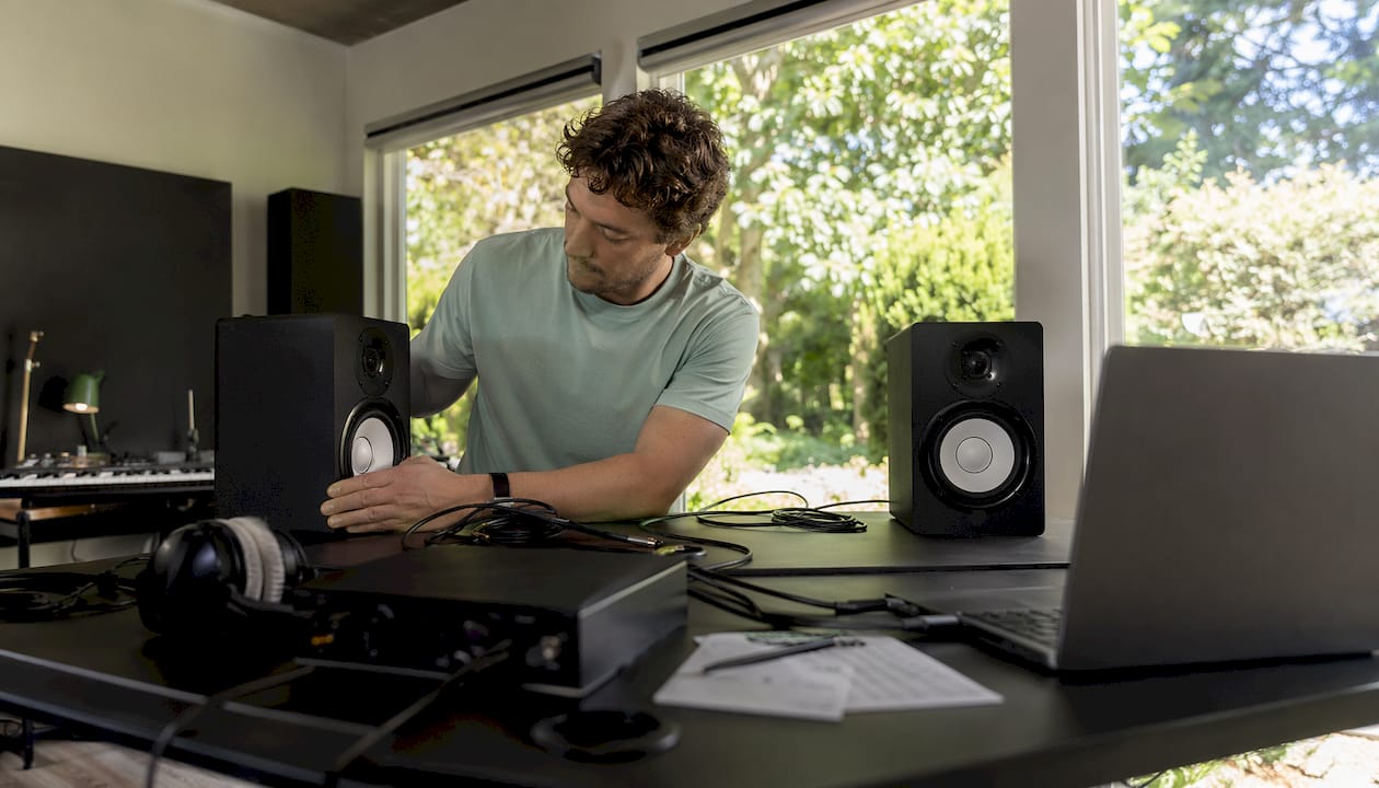 Hoe monteer je studio monitoren: complete installatiegids 3 Een muzikant richt zijn thuisstudio in en zet de studiomonitoren op de juiste plek.