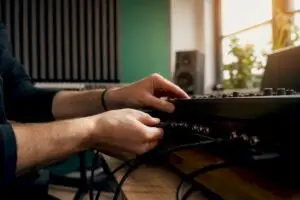 Handen die kabels aansluiten op een hardware-synthesizer